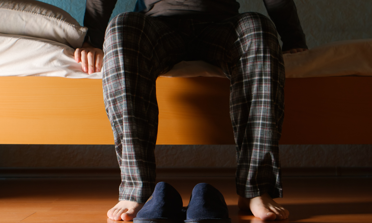 Man,sits,on,a,bed,in,the,night,at,home